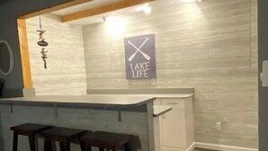 A kitchen with a bar area, wooden stools, and a sign that says "LAKE LIFE".