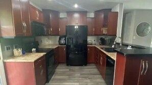 A modern kitchen with wooden cabinets, a central island, and a built-in refrigerator.