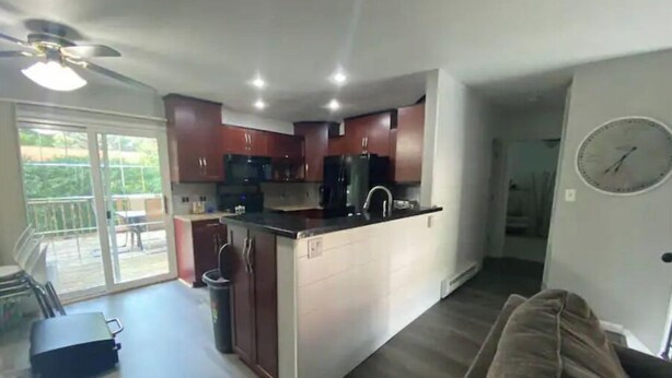 A spacious kitchen with a central island, a dining area with a table and chairs, and a large sliding glass door leading to a balcony.