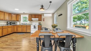 Una cocina con armarios de madera, una mesa de comedor con sillas y un ventanal con vistas a árboles.