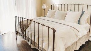 A neatly made bed with a metal frame, white bedding, and a bedside lamp.