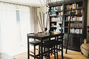 A room with a dark wooden dining table, chairs, a bookshelf, and a ladder.