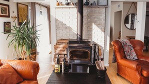 A cozy living room with a brick fireplace, leather sofas, and a potted plant.