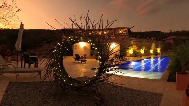 A pool area with a stone building, outdoor seating, and a decorative archway.