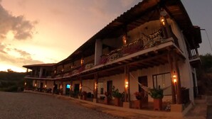 A two-story building with a balcony, outdoor seating area, and string lights.