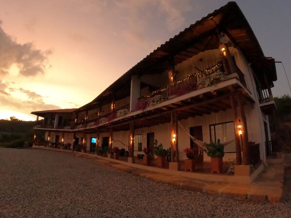 A two-story building with a balcony, outdoor seating area, and string lights. - Hotel Boutique Feria Internacional  (Bogotá)