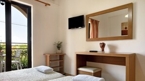 Ett hotellrum med två sängar, en TV, en spegel, ett skrivbord och utsikt genom ett stort fönster.