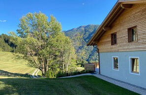 A wooden building with a mountain view, a lawn, and a small wooden structure.