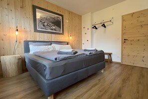 Ein Schlafzimmer mit einem Bett, Holzwänden, einem Bild, einem Nachttisch und einem Kleiderhaken.
