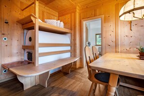 Ein Holzhütten-Interieur mit Etagenbett, einer Bank, einem Esstisch und Stühlen.