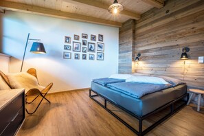 A bedroom with a bed, a chair, a desk, and wall-mounted lamps.