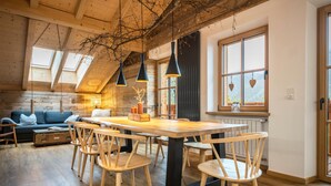 Un interior rústico de madera con zona de comedor, muebles de madera y ventanas grandes.