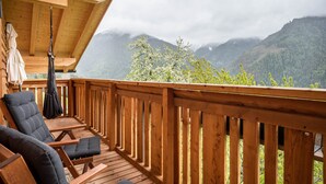 Terraza de madera con asientos exteriores y vistas a montañas.