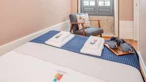 Quarto com cama, cadeira, janela e porta.