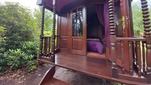 A wooden structure with a balcony, a door with glass panels, and a purple curtain.