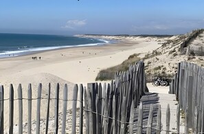 Una spiaggia con una recinzione in legno, una bicicletta e una riva sabbiosa.