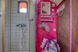 Un bagno con doccia, uno specchio e un mobile lavabo con una parete rosa.
