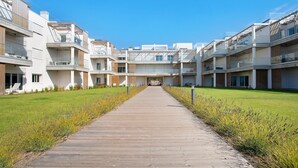 A modern residential building with a central courtyard, wooden deck, and balconies. - Apartment "Luxury Boho Style Nazaré" with Sea View, Shared Pool & Wi-Fi (Nazaré)