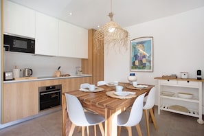 Una cucina moderna con mobili bianchi, un tavolo da pranzo in legno e un lampadario.