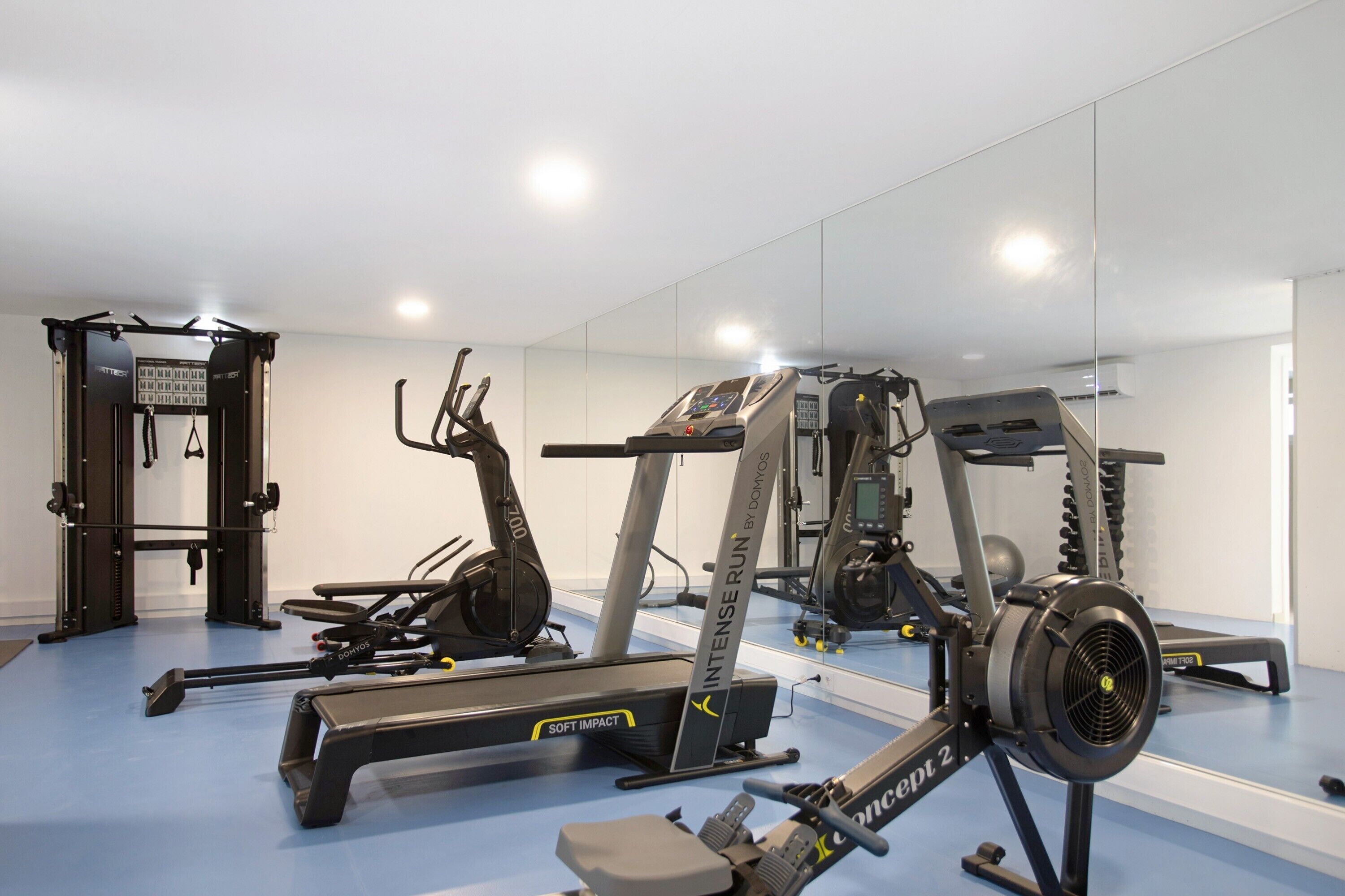 A gym with cardio machines, weightlifting equipment, and a mirrored wall.