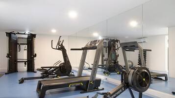 A gym with cardio machines, weightlifting equipment, and a mirrored wall.