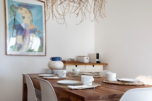 Una tavola imbandita con piatti, tazze e un vaso, con un quadro sopra e un lampadario.