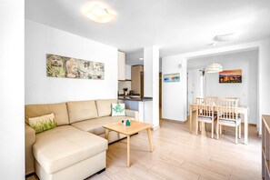 Ein modernes Wohnzimmer mit einer Couch, einem kleinen Tisch und einem Essbereich mit Stühlen.