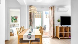 A modern living room with a dining area, a TV, and a plant. - Holiday Apartment 'Torreblanca Deluxe Holiday Home' with Sea View, Shared Pool & Wi-Fi (Fuengirola)