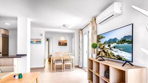 A modern living room with a TV, wooden furniture, and a view of a river. - Holiday Apartment 'Torreblanca Deluxe Holiday Home' with Sea View, Shared Pool & Wi-Fi (Fuengirola)
