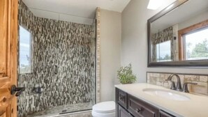 Een badkamer met douche, toilet, wastafel en een spiegel.