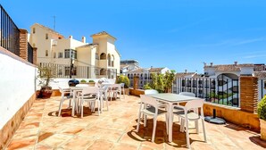 A rooftop patio with outdoor seating, a barbecue grill, and a view of surrounding buildings.