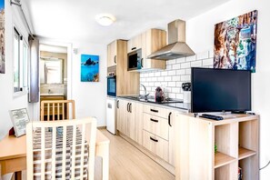 Une cuisine compacte avec des meubles en bois, une cuisinière encastrée, un four à micro-ondes et un grand téléviseur.