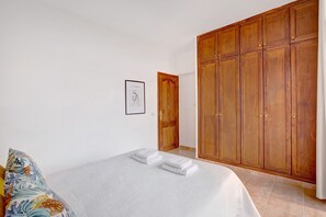 A bedroom with a bed, a wooden wardrobe, and a framed picture on the wall.