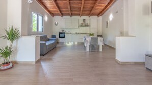 A modern kitchen with white cabinets, a dining table, and a wooden ceiling. - Villa Lorenzo with Private Garden, Whirlpool & Wi-Fi (Avola)