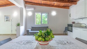 A modern kitchen with white cabinets, a dining table with a centerpiece, and a wooden ceiling. - Villa Lorenzo with Private Garden, Whirlpool & Wi-Fi (Avola)
