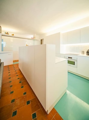 Una cucina moderna con mobili bianchi, un piano di lavoro e un pavimento piastrellato con motivo geometrico.