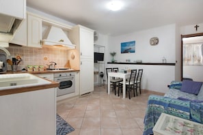 A compact kitchen with a dining area, a TV, and a bed with a window view. - Holiday Home 'Deiva' with Landmark View and Wi-Fi (Deiva Marina (SP))