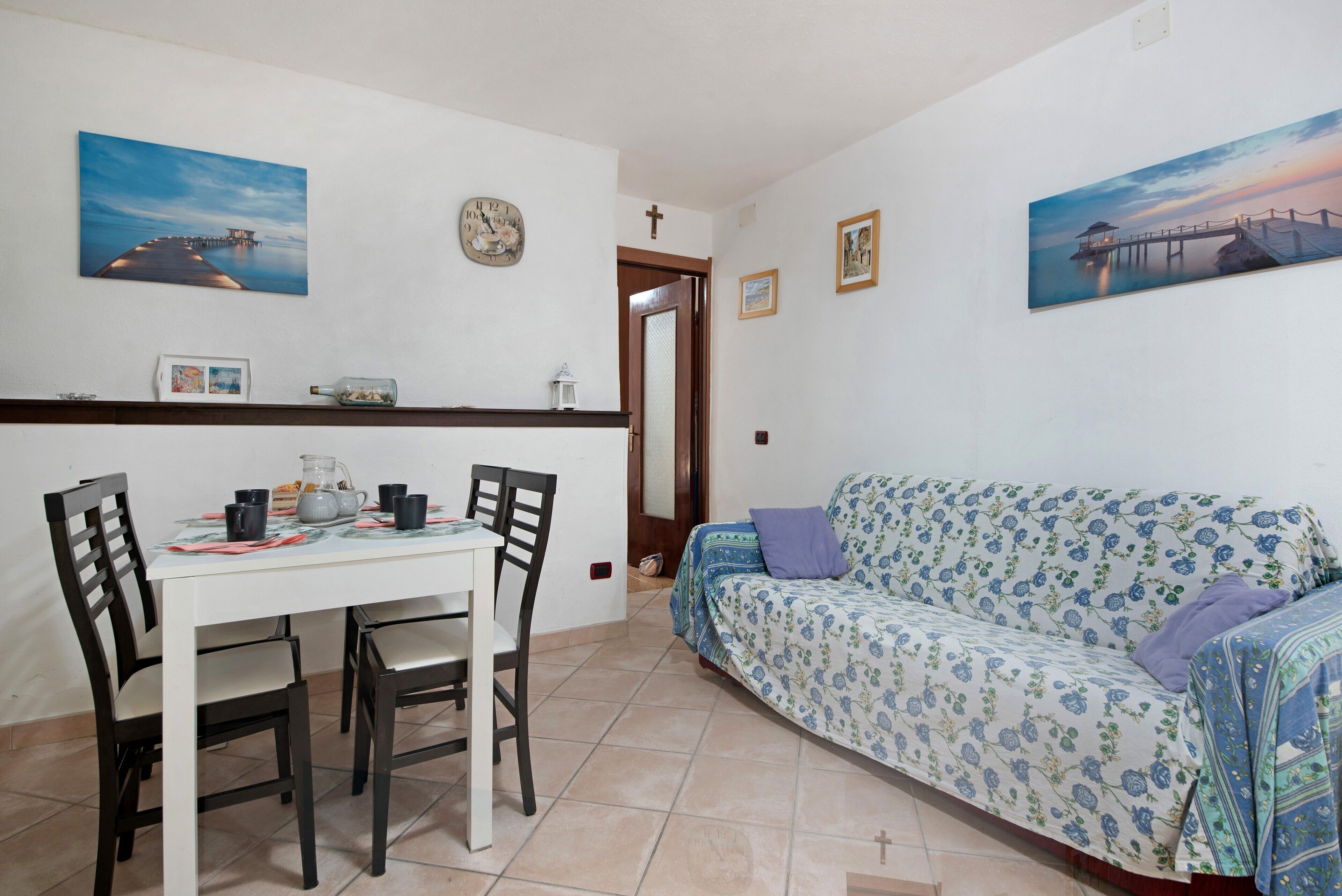 Un comedor con una mesa y sillas, un sofá y dos cuadros colgados en la pared.