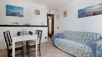 Un comedor con una mesa y sillas, un sofá y dos cuadros colgados en la pared.