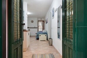 A narrow hallway leading to a bedroom with a bed, a small table, and a trash bin. - Holiday Home 'Deiva' with Landmark View and Wi-Fi (Deiva Marina (SP))