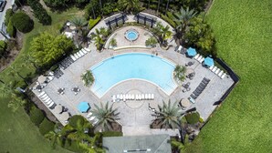 Luchtbeeld van een resort met een groot zwembad, ligbedden en palmbomen.