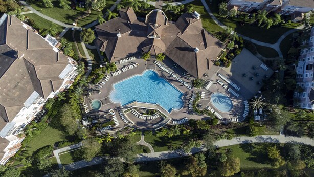 Luchtbeeld van een resort met een centraal zwembad, meerdere loungegebieden en diverse gebouwen met verschillende architectuurstijlen.