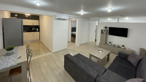 A modern apartment with a kitchen, dining area, living room, and a TV mounted on the wall. - Charming 2-bed Apartment in Kallithea (Kallithea)