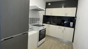 A compact kitchen with a refrigerator, stove, microwave, and cabinets. - Charming 2-bed Apartment in Kallithea (Kallithea)