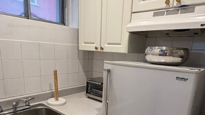 A kitchen with white cabinets, a stainless steel sink, a toaster, and a refrigerator.