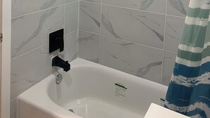 A bathroom with a bathtub, a showerhead, and a curtain.