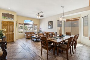 A spacious living area with a dining table, comfortable seating, and a ceiling fan.