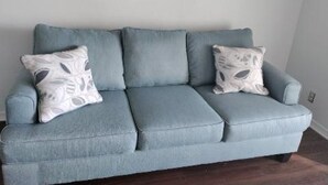 En lyseblå sofa med tre puder foran en ensfarvet væg.