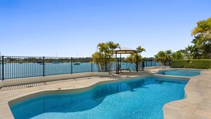 A swimming pool with a view of the sea, a covered seating area, and a fenced deck. - Commodore 7 80 Noosa Parade (Noosa Heads)