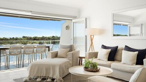 A modern living room with a view of a lake, a sofa set, a coffee table, and a lamp. - Commodore 7 80 Noosa Parade (Noosa Heads)